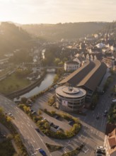 Aerial view of a town with a river, buildings and streets surrounded by hills at sunset, Calw,