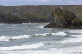 Coastal landscape with imposing cliffs and high waves, blue sky