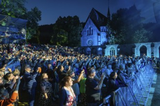 Large crowd at a night concert in front of a church, stage illuminated in blue, Klostersommer, Calw