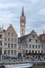 Striking Gothic buildings with clock tower along the river, bustling with people, Ghent