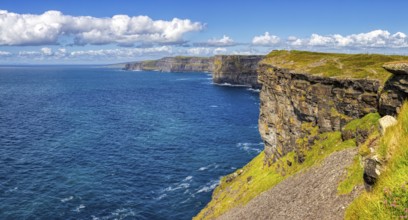 Sunlit cliffs on an endless blue coastline under a clear sky, Cliffs of Moher