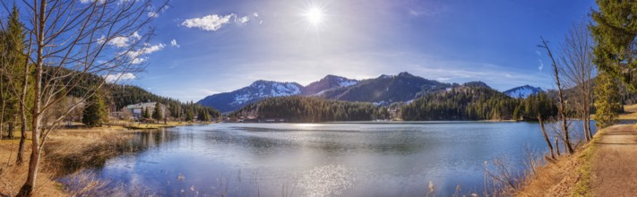 Large mountain lake with calm water surface, sunshine and picturesque mountain landscape,