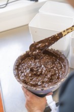 Hand holding a bowl of melted chocolate and stirring it, Burch Schokolade production, Haselstaller