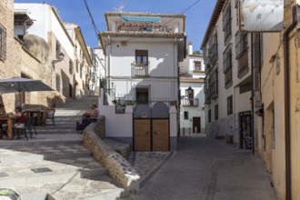 Sunny street with traditional buildings and a café, peaceful atmosphere, Granada