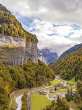 View of the valley with winding river and small settlement under wooded mountains, Switzerland,