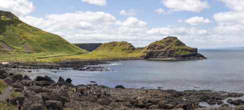 Coastal landscape with green cliffs and rocks by the sea under a blue sky, Giant Causeway