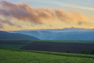 Landscape with fields and mountains in the background, clouds in the sky at sunrise, autumn,