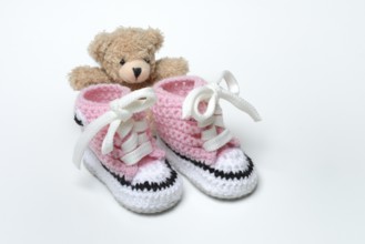 Baby shoes and teddy bear, white background