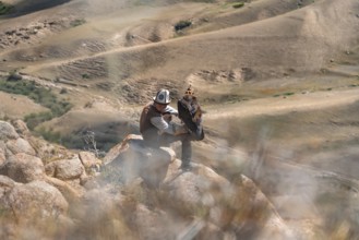 Traditional Kyrgyz eagle hunter hunting in the mountains in a dry landscape, near Kysyl-Suu, Issyk