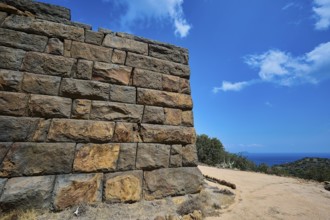 Ancient ruined wall in an arid landscape with a view of the sea and a clear blue sky, Palaiokastro,