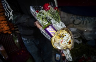 Vendor shows a rose and chocolate bouquet in a street flower shop, on the occasion of Valentines