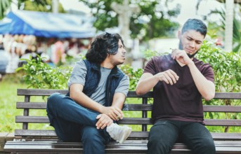 Man smoking and exhaling smoke to another person near him. Man smoking cigarette near people in