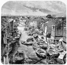 Wooden houses and sandy paths along a canal in old Tokyo, many rowing boats for transporting people