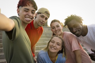 Happy friends of different cultures and races taking a selfie in the sunset light. Concept of youth