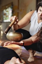 Latin yoga teacher with a singing bowl inducing relaxation at the end of yoga class. Vertical