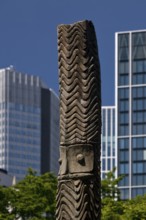 Stele made of carved wood from Papua New Guinea at the Weltkulturen Museum in front of skyscrapers,