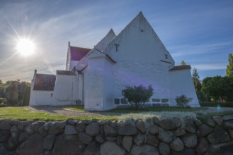 Whitewashed church in Dalby, backlight, stone wall made of boulders, Fyn, North Funen, Denmark,