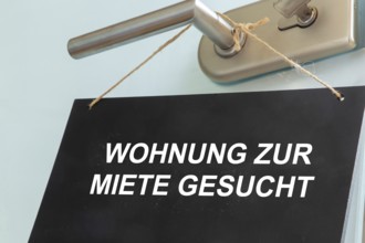 Sign with the words WOHNUNG ZUR MIETE GESUCHT on a door (symbolic image)