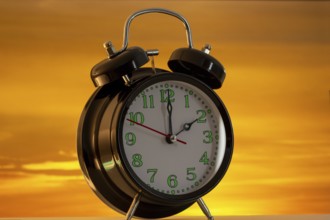 Symbolic image of the time change to summer time: close-up of an alarm clock in front of a