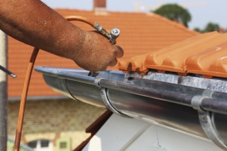 Roofer doing tinsmith work on a gutter