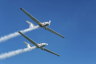 Stunt aerobatic plane performing stunts in blue sky with smoke trail. Concept of teamwork,