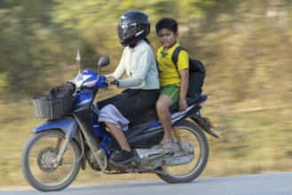 Mother with her son in school uniform on a motorbike, Vang Vieng, Vientiane province, Laos, Asia