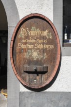 Old wine barrel on a house wall with artistic lettering and painting as a decorative advertising