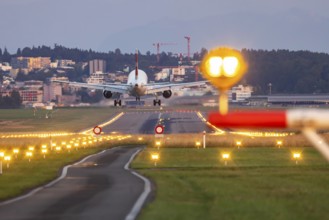 Aircraft of the airline Swiss landing in the evening with illuminated runway. Zurich Airport,