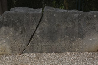 Close-up of carved letters on broken split in two large and heavy block of old weathered limestone