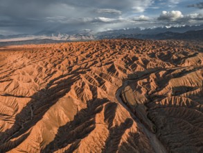 Landscape of eroded hills, badlands at sunset, mountain peaks of the Tian Shan Mountains in the