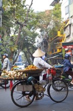 Vietnamese street vendor with conical hat and bicycle in the Old Quarter of Hanoi, Vietnam, Asia