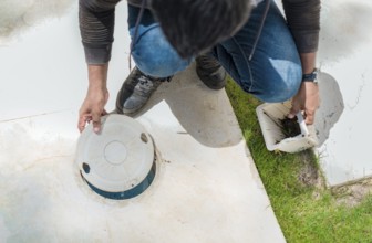 Cleaning and maintenance of the swimming pool skimmer basket. Person cleaning pool filter skimmer