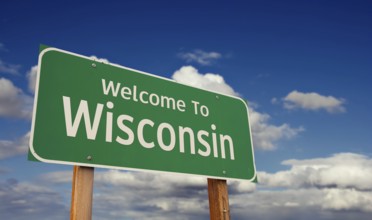 Welcome to wisconsin green road sign over blue sky with some clouds