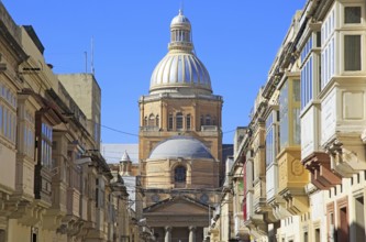 Traditional houses with balconies dome of Paola parish church, Tarxien town, near Valletta, Malta,