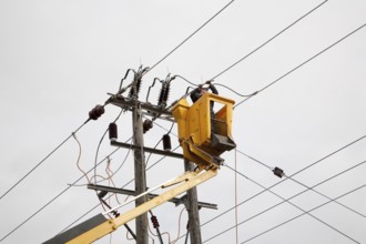 Electrician working in cherry picker connecting high voltage power lines at Bucklesham, Suffolk,