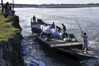 Public Works Department (PWD) of Assam labourer throwing sand bag from boat in the banks of Beki