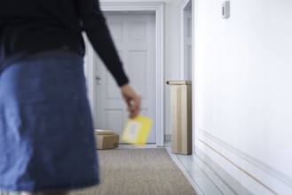 A woman walks through a stairwell in Berlin with a parcel collection note, 08/08/2024