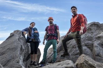 Group of diverse climbers celebrating triumph atop a breathtaking mountain summit, facing camera