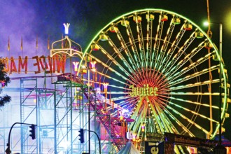 Cranger Kirmes with colourfully illuminated fairground rides and the Ferris wheel at night, Herne,