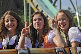 Three pretty funny girls in dirndls show Victoty sign, hand gesture V for Victory, victory, white