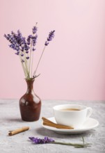 Purple lavender in ceramic jug and a cup of coffee on a gray and pink background. Morninig, spring,