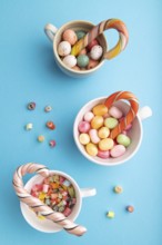 Heap of multicolored caramel candies in cups on blue pastel background. close up, top view, flat