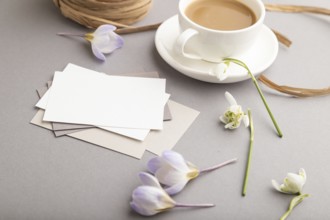 White paper business card mockup with spring snowdrop crocus and galanthus flowers and cup of