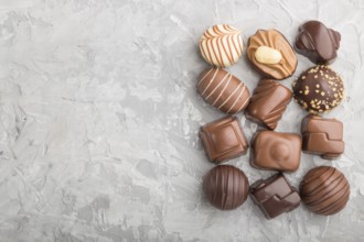 Different chocolate candies on a gray concrete background. top view, flat lay, copy space