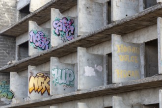 Lost Place, Unfinished concrete building with colourful graffiti on the walls, urban atmosphere,