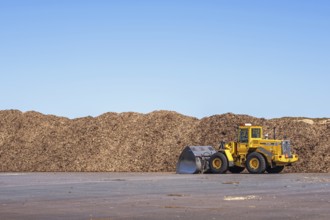 Loader at big stacks of wood chips for solid biomass fuel, Falköping, Sweden, Europe