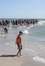 Ttourists standing at the northern tip of Denmark where the Baltic Sea and North Sea meet at Skagen