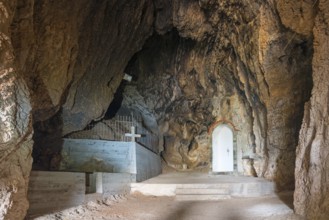 Interior view of a rocky cave with a tomb and a cross, a white niche visible, Church of Mary the