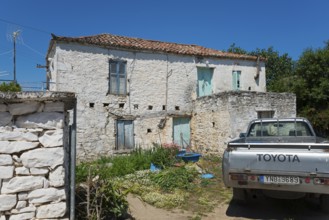 Old stone house with a Toyota pickup truck in the foreground in a rural setting, Taktikoupolis,