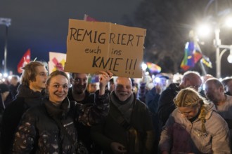 Participants with sign Remigrate yourselves to your knees!!! at the demonstration under the motto